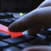 Computer keyboard with red enter key being pressed