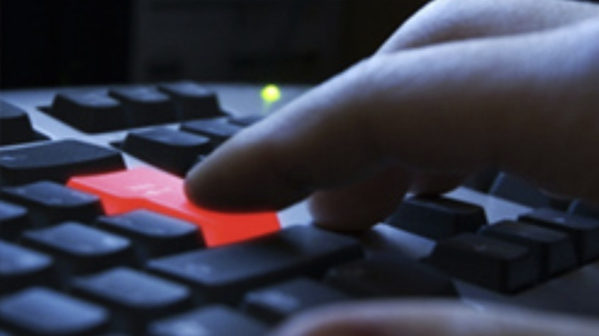 Computer keyboard with red enter key being pressed