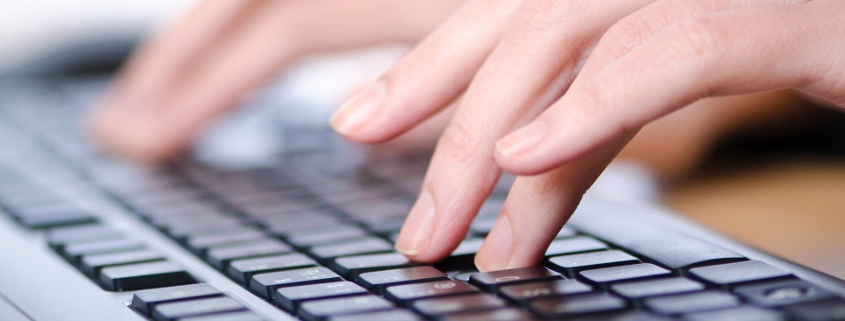 Hands typing on computer keyboard